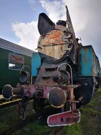 Abandoned train on field against sky