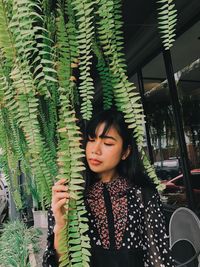 Woman standing by plant in cafe