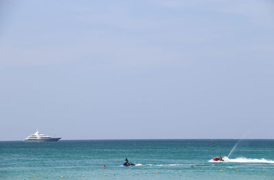 People in jet boats on sea against clear sky