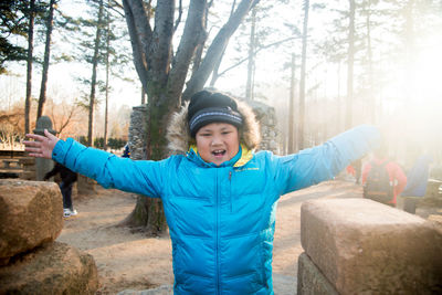 Portrait of smiling young woman standing in forest