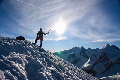 Low angle view of man standing on snowcapped mountains against sky