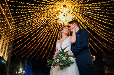 Full length of couple holding illuminated lighting equipment