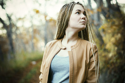 Young woman standing against tree
