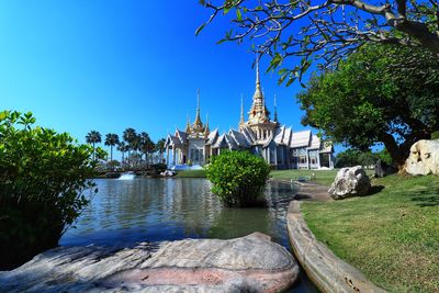 Temple by building against clear blue sky