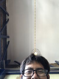 Portrait of woman with eyeglasses against wall