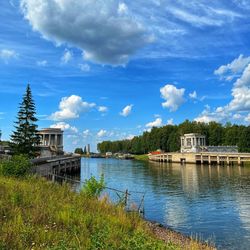 Buildings by river against sky