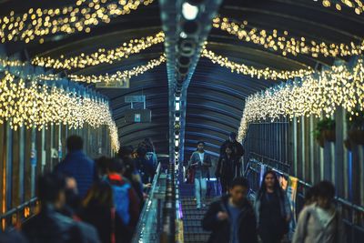 People walking in illuminated covered footbridge