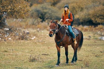 Full length of a young woman riding horse