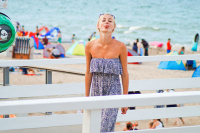 Portrait of young woman sticking out tongue at beach