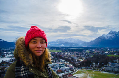 Portrait of woman against residential district against cloudy sky