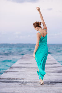 Rear view of woman walking on pier against sea