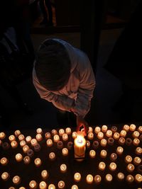 Midsection of man holding illuminated candles