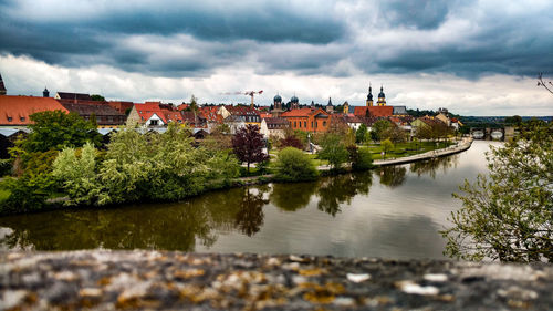 Scenic view of river by city against sky