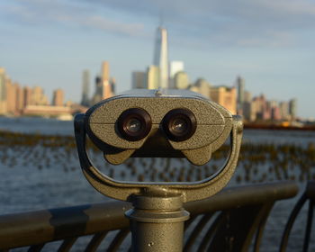 Close-up of coin-operated binoculars with buildings in backgrounds