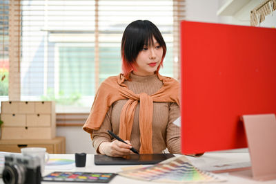 Side view of young woman using mobile phone at home