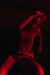Side view of young man sitting against black background