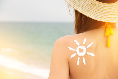 Rear view of woman with arms raised against sea