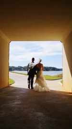 Rear view of wedding couple standing in tunnel