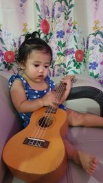 Cute girl playing guitar at home