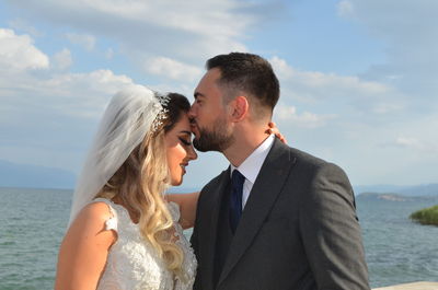 Side view of couple standing against sky