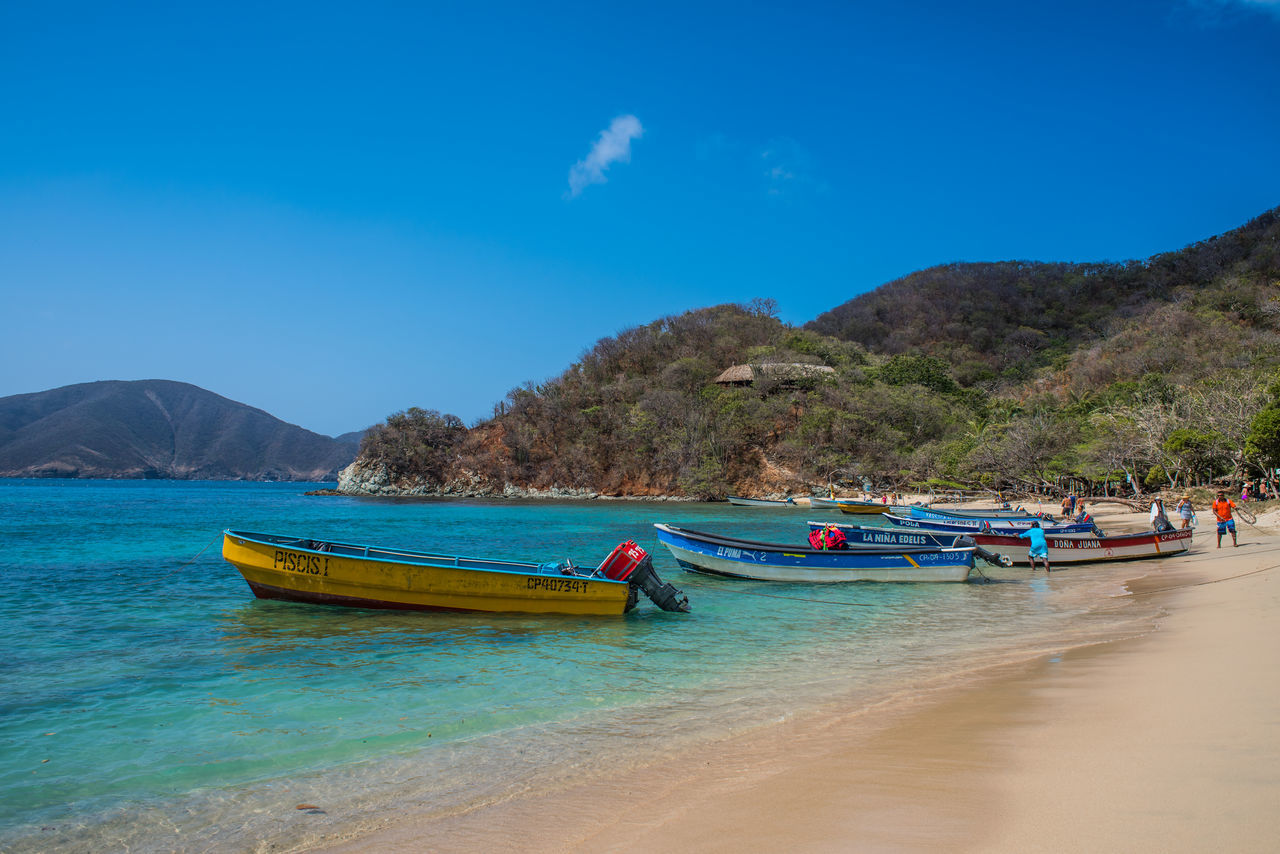 FISHING BOATS MOORED ON SEA AGAINST BLUE SKY