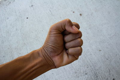 Cropped hand clenching fist against wall