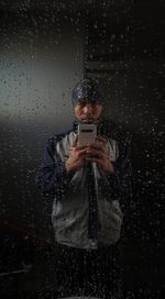 Portrait of man with umbrella standing in rain