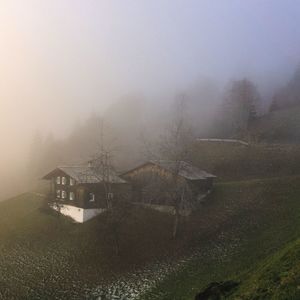 Scenic view of fog over land and houses against sky