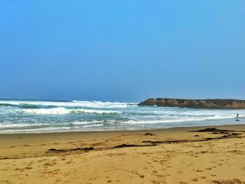 Scenic view of beach against clear blue sky