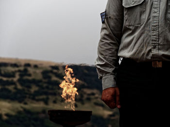 Midsection of man standing by fire