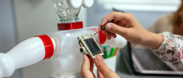 Female student screwing solar panel on recycled toy robot in a robotics class