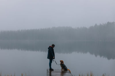 Man with dog on pier by lake