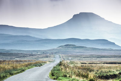 Road leading towards mountains against sky