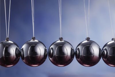 Close-up of metal balls hanging against blue background