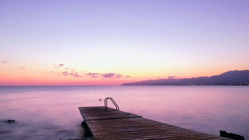 Pier over sea against sky during sunset