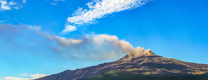 Panoramic view of volcanic mountain against blue sky