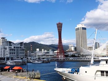 Sailboats moored on harbor by buildings against sky