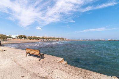 Empty benches on beach against blue sky