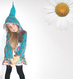 Digital composite image of daisy and girl wearing dwarf hat against white background