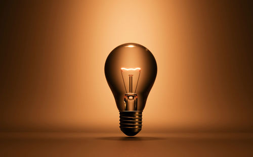 Close-up of illuminated light bulb against wall