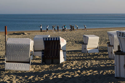 Hooded chairs on beach by sea against sky