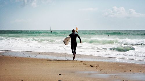 Full length of man standing on beach against sky