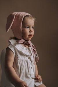 Cute girl looking away while standing against gray background