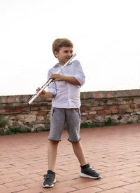 Full length of a child playing flute outdoors.