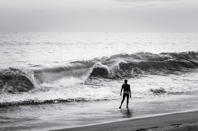 Rear view of man with surfboard on beach