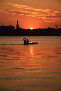 Silhouette boats in sea against sky during sunset