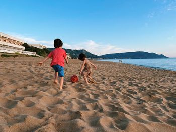 Boy and girl playing football at the beach 