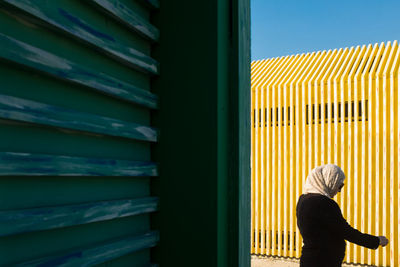 Rear view of woman standing against building