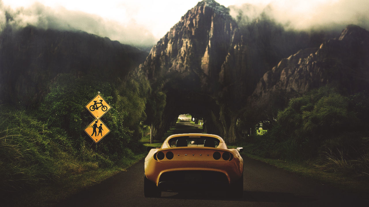 CAR ON ROAD BY MOUNTAINS