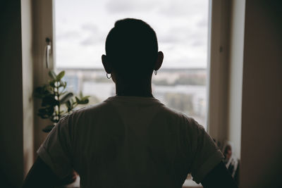 Rear view of man standing against window